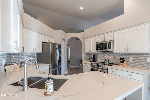 kitchen with light stone counters, decorative backsplash, white cabinetry, and stainless steel appliances