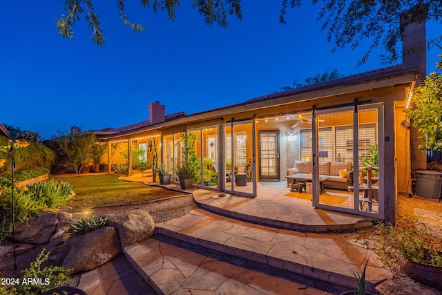 back house at night featuring a patio and a yard