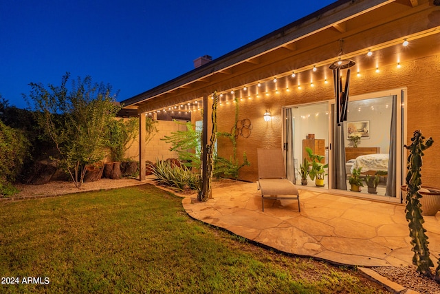 patio at night featuring a lawn