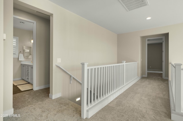 corridor featuring visible vents, carpet flooring, baseboards, and an upstairs landing