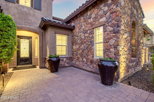 exterior entry at dusk featuring a patio area