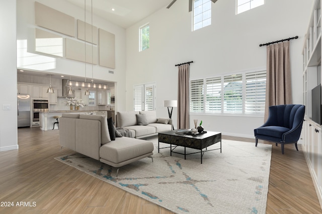 living room featuring a towering ceiling, hardwood / wood-style floors, ceiling fan, and plenty of natural light