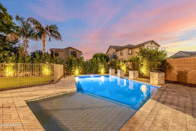 pool at dusk with a patio area