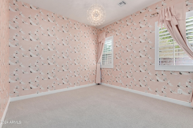 carpeted empty room featuring an inviting chandelier and a wealth of natural light