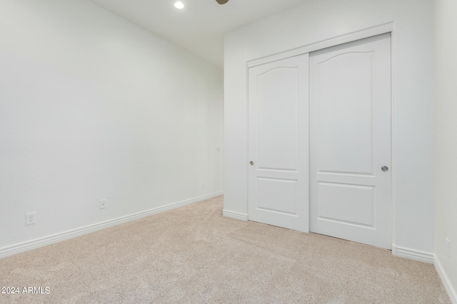 unfurnished bedroom with light colored carpet and a closet