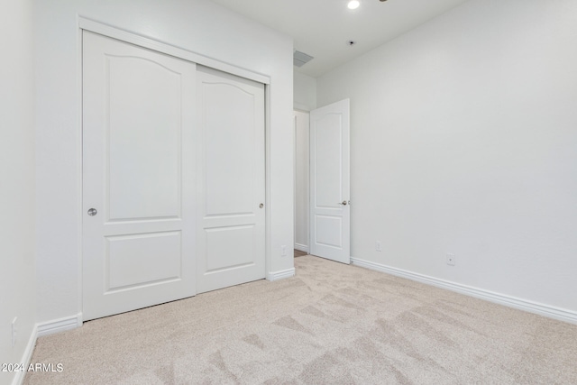 unfurnished bedroom featuring light carpet and a closet