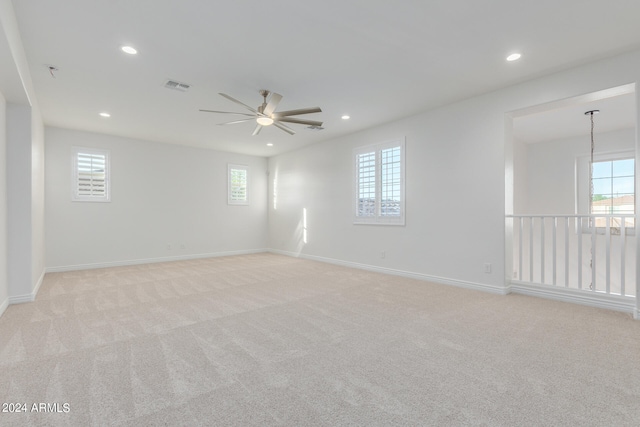 unfurnished room with ceiling fan, light colored carpet, and a wealth of natural light