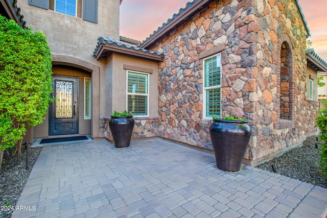 exterior entry at dusk featuring a patio area