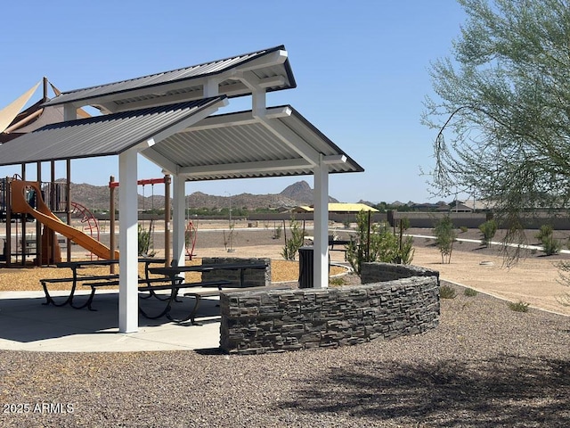 surrounding community featuring a playground and a mountain view