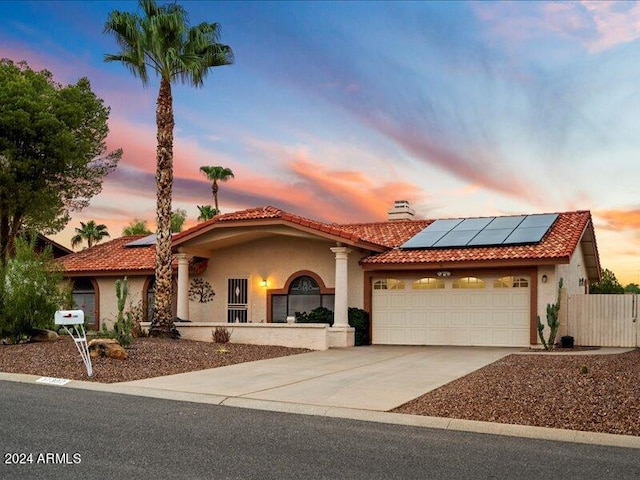 mediterranean / spanish-style home with a garage and solar panels