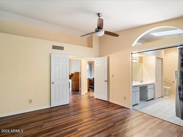 unfurnished bedroom featuring hardwood / wood-style flooring, ceiling fan, and ensuite bath