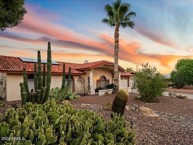 mediterranean / spanish-style home featuring solar panels and a garage