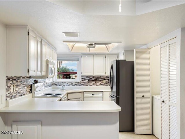 kitchen featuring backsplash, white cabinetry, a textured ceiling, white appliances, and kitchen peninsula