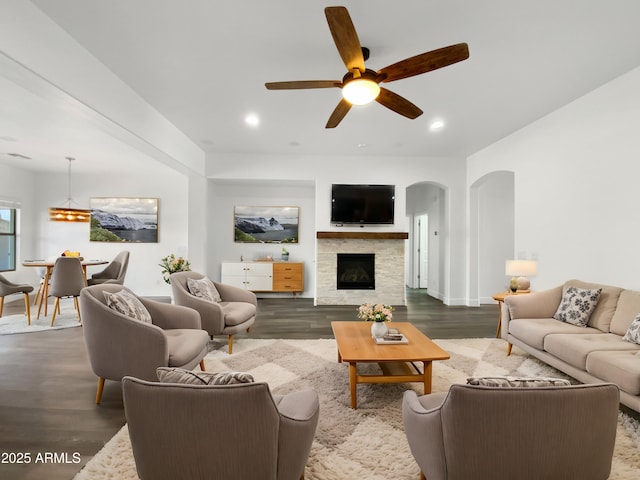 living room featuring a tile fireplace, ceiling fan, and dark hardwood / wood-style flooring