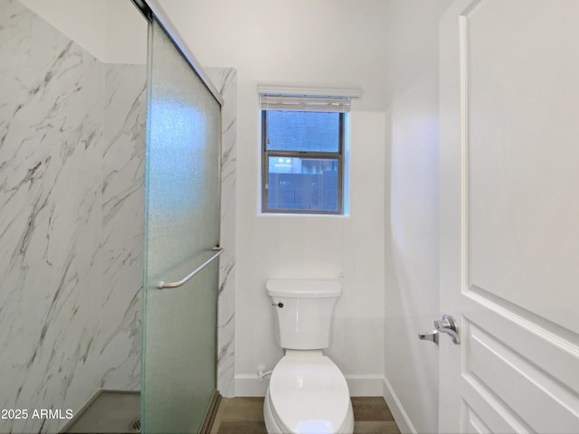 bathroom featuring toilet and a shower with shower door