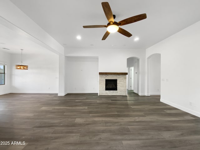 unfurnished living room featuring a fireplace, dark hardwood / wood-style floors, and ceiling fan