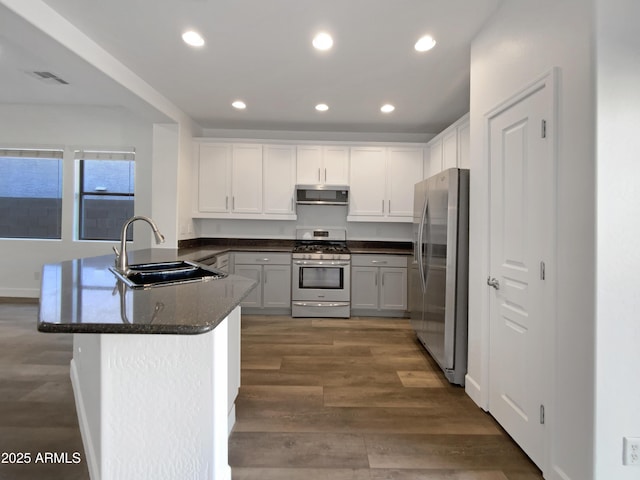 kitchen with dark stone counters, white cabinets, sink, kitchen peninsula, and stainless steel appliances