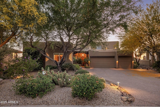 pueblo-style home with stucco siding, driveway, and an attached garage