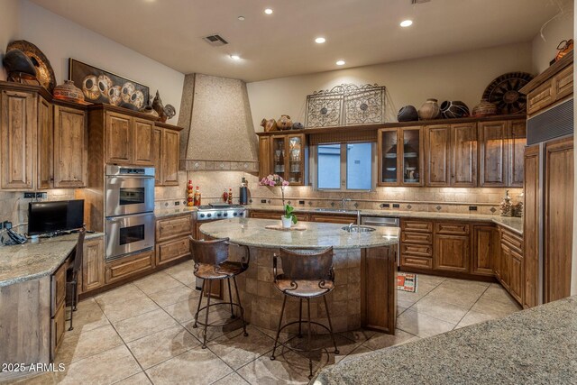 kitchen featuring stainless steel double oven, custom range hood, backsplash, recessed lighting, and light tile patterned floors