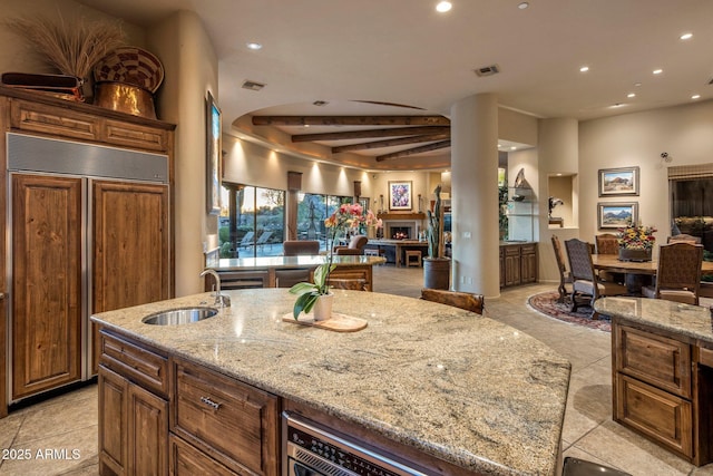kitchen with paneled built in refrigerator, open floor plan, a sink, recessed lighting, and light stone counters