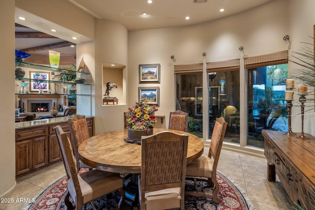 dining space with recessed lighting, a lit fireplace, and light tile patterned floors