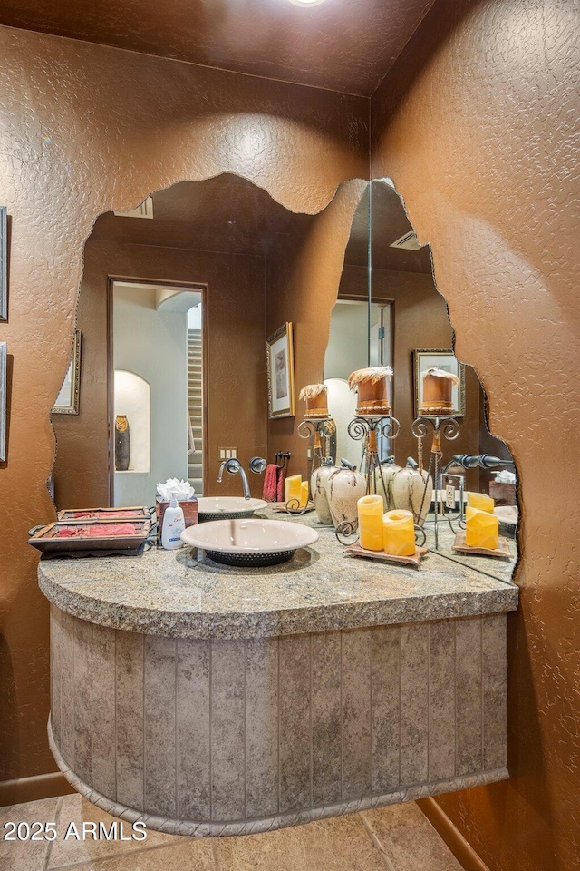 bathroom with a textured wall and vanity