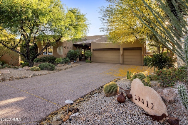 adobe home featuring asphalt driveway, stucco siding, an attached garage, and a tile roof