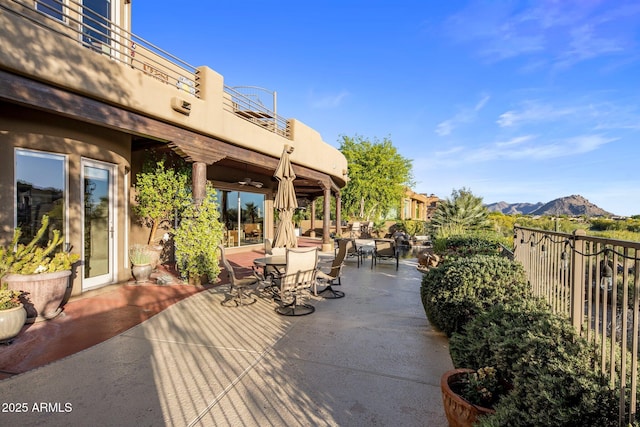 view of patio featuring a mountain view, outdoor dining area, and a balcony