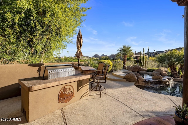 view of patio featuring area for grilling, an outdoor bar, and fence