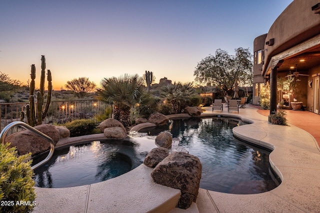 pool at dusk with a patio area and an in-ground hot tub