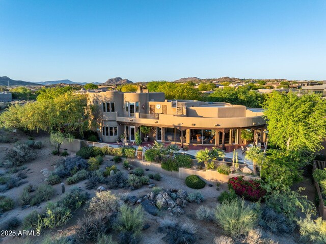 back of property featuring a mountain view, fence, and stucco siding