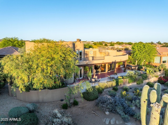 rear view of property with a balcony, stucco siding, a patio, and fence