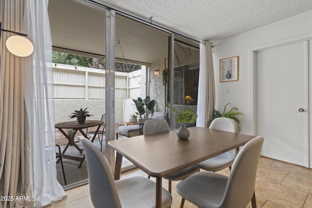 tiled dining area with a textured ceiling and a wall of windows