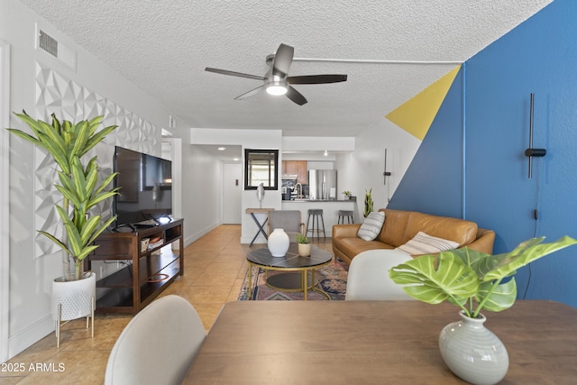 tiled living room featuring ceiling fan and a textured ceiling