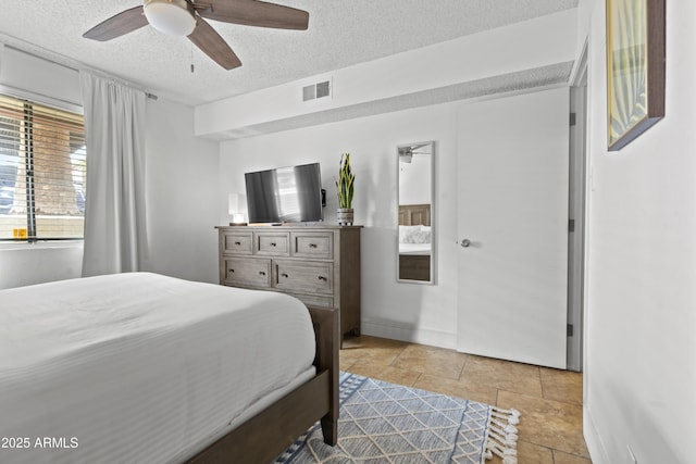 tiled bedroom featuring ceiling fan and a textured ceiling