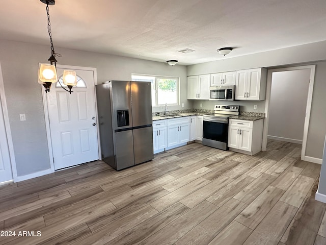 kitchen featuring decorative light fixtures, light hardwood / wood-style flooring, white cabinetry, appliances with stainless steel finishes, and an inviting chandelier