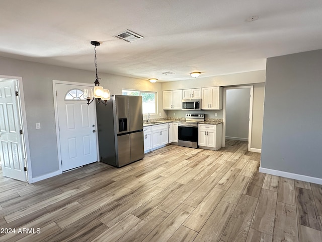 kitchen featuring appliances with stainless steel finishes, hanging light fixtures, white cabinetry, light wood-type flooring, and a notable chandelier