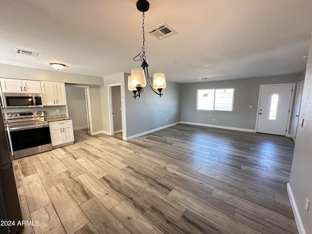 kitchen with a notable chandelier, white cabinets, appliances with stainless steel finishes, and light wood-type flooring