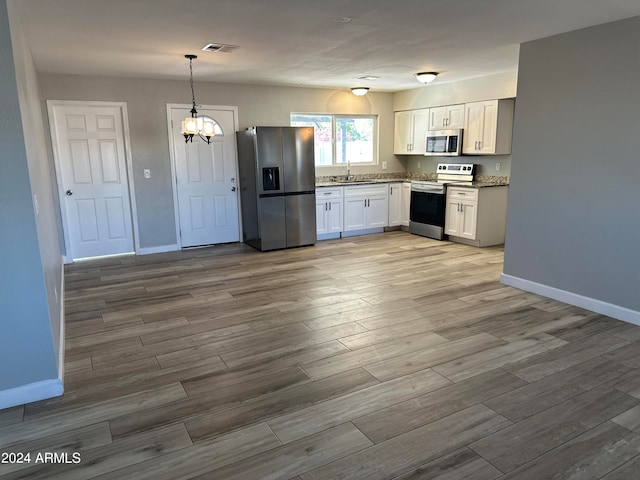 kitchen featuring appliances with stainless steel finishes, hardwood / wood-style floors, pendant lighting, and white cabinets