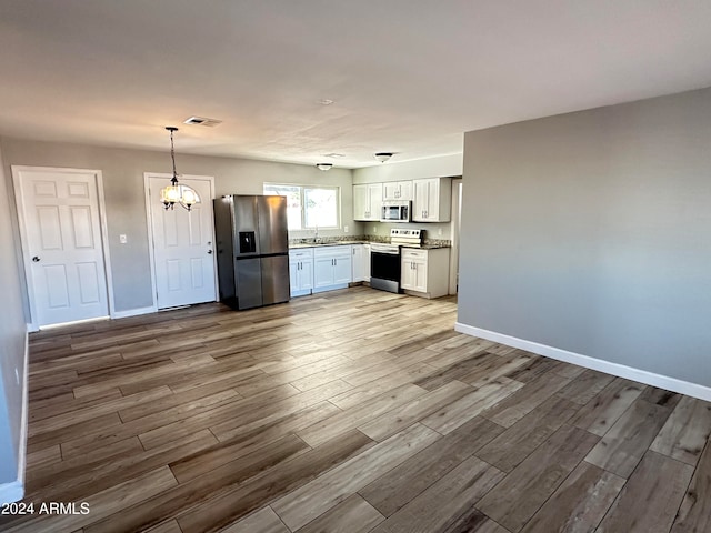 kitchen with light hardwood / wood-style flooring, stainless steel appliances, white cabinetry, and an inviting chandelier