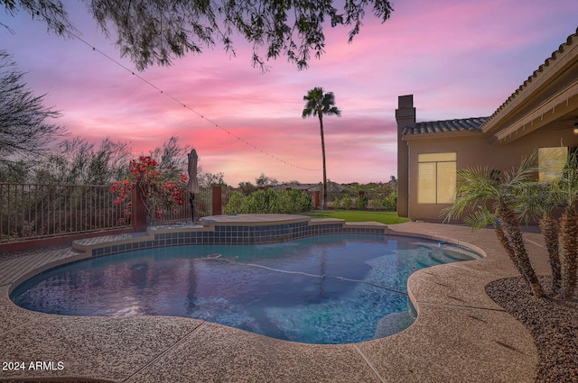 pool at dusk with a hot tub