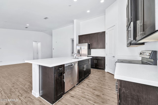 kitchen with a kitchen island with sink, dark brown cabinets, stainless steel appliances, and sink