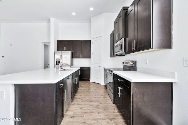 kitchen featuring light hardwood / wood-style flooring, sink, stainless steel appliances, and an island with sink