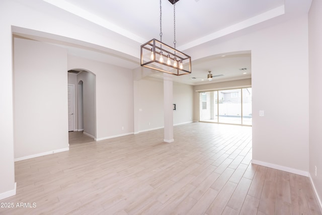 unfurnished room with ceiling fan with notable chandelier and light hardwood / wood-style floors