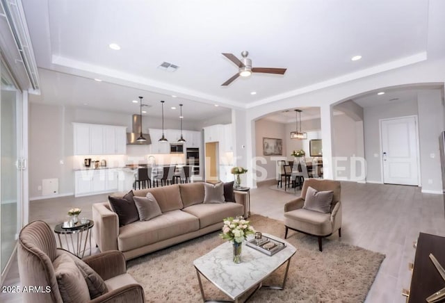 living room with ceiling fan with notable chandelier and light hardwood / wood-style floors