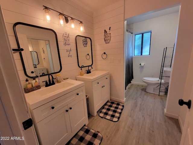 bathroom featuring wood-type flooring, toilet, vanity, and wood walls