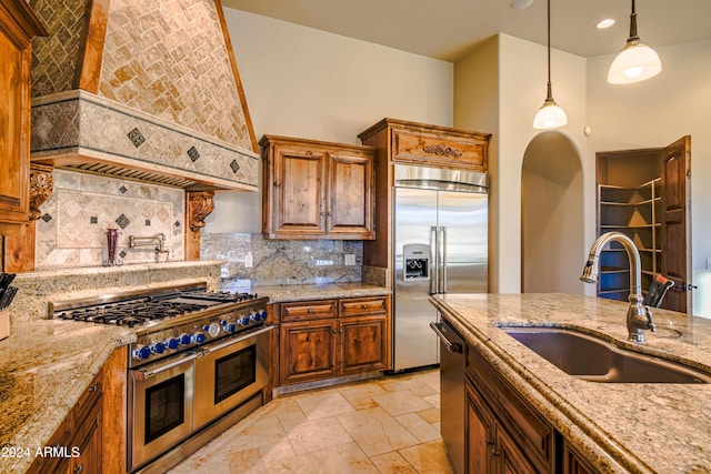 kitchen featuring pendant lighting, sink, high quality appliances, light stone countertops, and custom exhaust hood