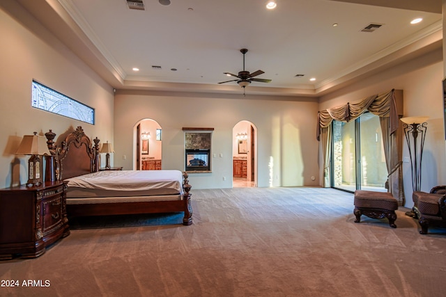 carpeted bedroom with ensuite bath, ornamental molding, a tray ceiling, and access to exterior