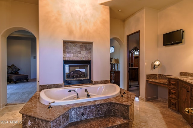 bathroom featuring vanity, tiled tub, and a fireplace