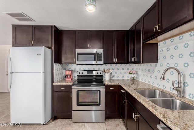 kitchen featuring stainless steel appliances, dark brown cabinets, a sink, and visible vents